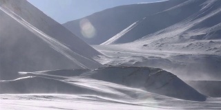 一个孤独的旅行者正穿过暴风雪，背景是雪山。