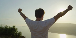 一个人举起手臂站在海洋悬崖上