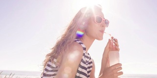在阳光明媚的夏日，女孩在海滩上喝着柠檬水