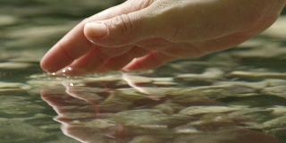 慢动作特写:手抓住和举起水晶清澈的水