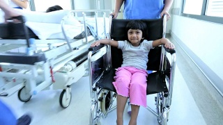 小女孩轮椅推着繁忙的医院走廊视频素材模板下载