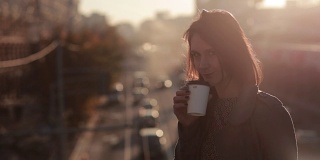 美丽的女人在城市桥上喝咖啡