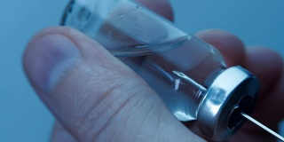 从蓝色背景的小瓶中取出疫苗，装入玻璃注射器。宏