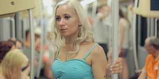 美丽的金发美女在拥挤的地铁车厢里看书