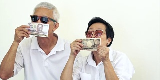 快乐，有钱，酷，有钱的亚洲老年人。向空中扔钱