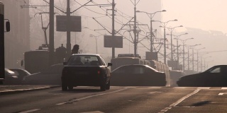 大雾弥漫，清晨的城市交通。欧洲塞尔维亚贝尔格莱德市。日出为背景，车辆和行人的剪影