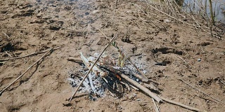 妇女在烤鱼下添加小树枝以保持炉火燃烧