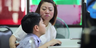 亚洲孩子在图书馆和他们的老师在看电脑在小学