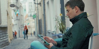 一个拿着平板电脑的成年人坐在街上