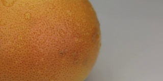 极端特写的橙子葡萄柚的露珠围绕着它的轴旋转