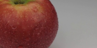 极端特写红苹果在水滴露珠旋转它的轴