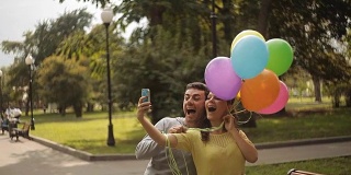 这对情侣在公园里和气球一起自拍