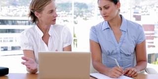 两个女商人一边工作一边使用笔记本电脑