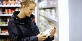一个女人把一瓶牛奶放在她的购物篮里
