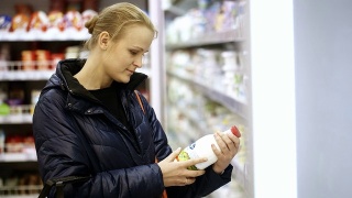一个女人把一瓶牛奶放在她的购物篮里视频素材模板下载