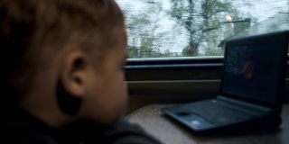 男孩在火车上用笔记本电脑看电影或卡通
