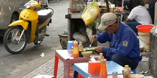 胡志明/西贡，越南——2015年:一个人在街上吃东西