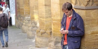 一名年轻人站在人行道上用智能手机输入信息