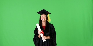 年轻激动的女人毕业在长袍与文凭