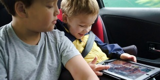 Boys with tablet computer during traveling by car