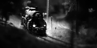 一辆玩具火车头和几辆货车四处走动的黑白画面