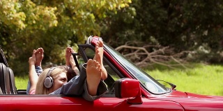 女孩们在一辆红色的车里听音乐