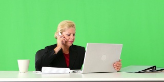 在办公桌上用手机和笔记本电脑工作的女高管