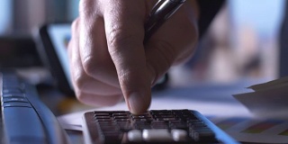 会计业务人员使用计算器在办公桌上填写纳税申报单