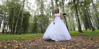 新娘穿着婚纱带着花束在公园里散步