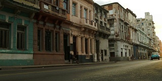两辆老爷车驶过哈瓦那的一条老街