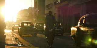 在哈瓦那的夕阳下，一排老爷车在车流中穿行