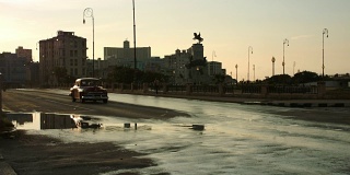 一辆老爷车和一辆摩托车停在哈瓦那一条潮湿的街道上