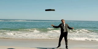 Happy businessman throwing his suitcase on the beach