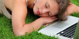 快乐的学生睡在草地上的笔记本电脑前