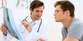 一位年轻的医生正在和他的病人讨论x光