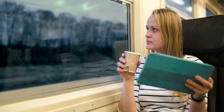 在火车上拿着触摸板和茶的女人