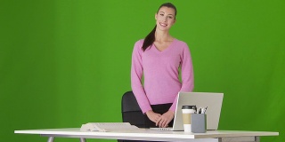 年轻的女商人拿着笔记本电脑站在办公桌前的肖像