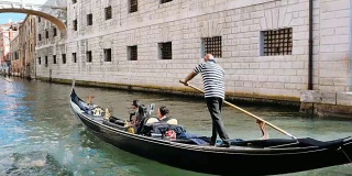 威尼斯运河上从桥下经过的贡多拉