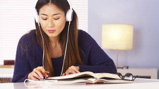 亚洲女人一边听音乐一边做作业视频素材模板下载
