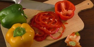 在切菜板上切甜椒，包括红、黄、绿