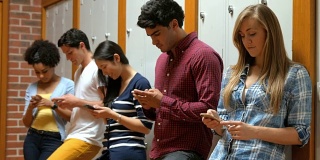 学生们靠在储物柜上用智能手机