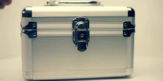 金属手提箱在白色背景上旋转，双手打开和关闭它