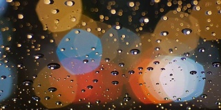 雨点落在挡风玻璃上，五边形灯光散焦。