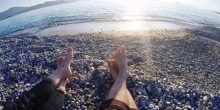 30多岁的年轻情侣在海滩上晒日光浴，向海里扔石头。观点