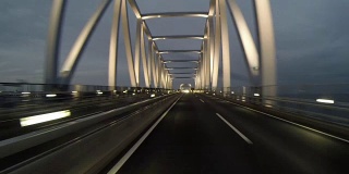 黄昏的后视图开车通过灯火通明的东京门大桥。