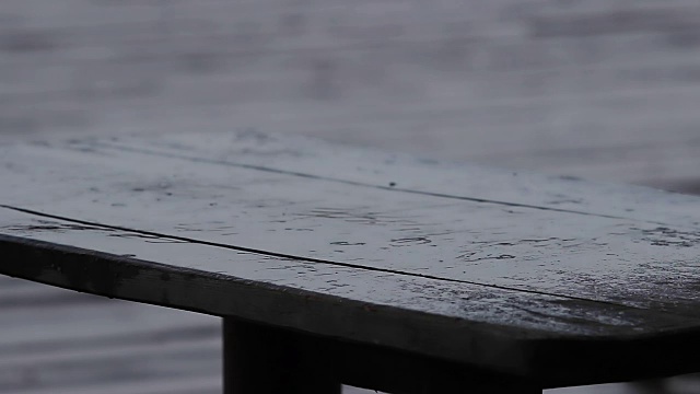 清澈的雨滴落在木桌上。悲伤的和多雨的