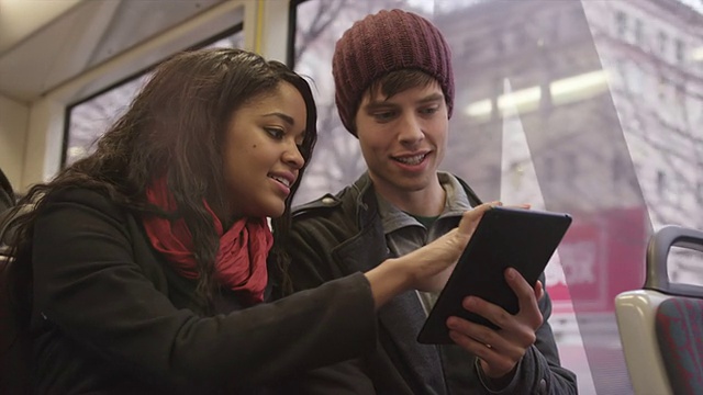 一对年轻情侣在火车上用平板电脑约会