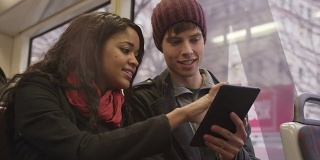 一对年轻情侣在火车上用平板电脑约会