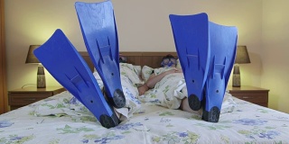 夏天的酒店房间里，穿着脚蹼和面罩的男女潜水员躺在床上