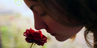 美丽的女孩闻着红玫瑰